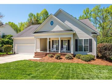 Charming home with rocking chairs on the porch and a manicured lawn at 11778 Crossroads Pl, Concord, NC 28025