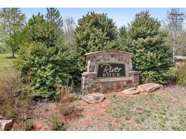Stone 'River Rock' community sign surrounded by lush greenery, creating an inviting entrance at 123 Pumice Dr, Statesville, NC 28625