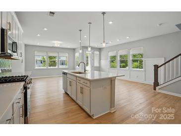 A bright kitchen with a kitchen island, hardwood floors, recessed lighting, and stainless steel appliances at 134 Berkeley Ave, Mooresville, NC 28117