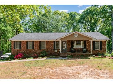 Charming brick home featuring a well-manicured lawn and an inviting front porch, perfect for relaxing at 1565 Oakridge Dr, Salisbury, NC 28146