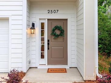 Inviting front entrance with a tan door, classic black lantern, and decorative green wreath at 2507 Elon St, Charlotte, NC 28208