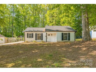 Charming single-story home with a white brick facade, black shutters, and a well-manicured lawn surrounded by mature trees at 4336 Valeview Ln, Charlotte, NC 28269