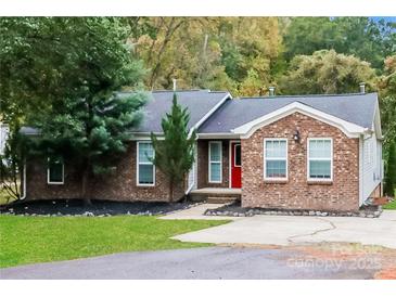 Charming brick home with a manicured lawn, a vibrant red door, and mature trees in a serene setting at 4989 Post Oak Ln, Rock Hill, SC 29732