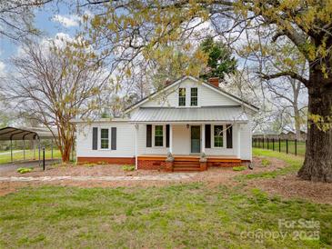 Charming white cottage with metal roof, black shutters, and inviting front porch surrounded by mature trees at 589 Lippard Farm Rd, Statesville, NC 28625