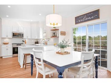 Eat-in kitchen featuring a breakfast bar, white cabinets, and stainless steel appliances, plus sliding glass doors and view at 220 Chandeleur Dr, Mooresville, NC 28117