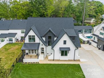 Stunning aerial view of a modern two-story home with black roof, white brick, and a well-manicured lawn at 5511 Fairview Rd, Charlotte, NC 28209