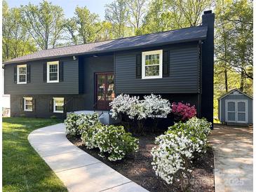 Charming two-story home with dark exterior, landscaped yard, flowering bushes, and a concrete walkway at 7507 Limerick Dr, Charlotte, NC 28270