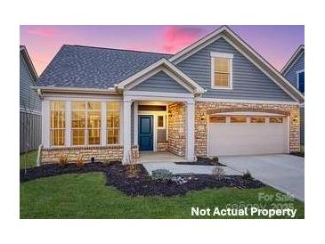 Charming home with stone accents, a two-car garage and well-manicured lawn at 7549 Baybrooke Ln # 32, Harrisburg, NC 28075