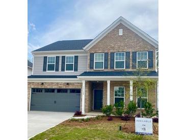 Two-story home features a brick facade, gray siding, a two-car garage, and a well-manicured lawn at 13748 Roderick Dr # 174, Huntersville, NC 28078