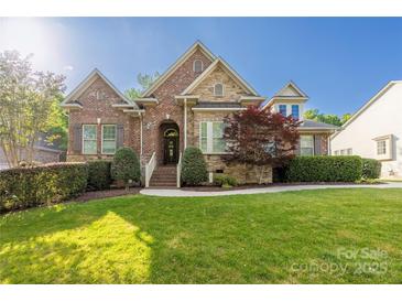Charming home with a brick and stone facade, lush green lawn, and manicured landscaping at 15024 Old Vermillion Dr, Huntersville, NC 28078
