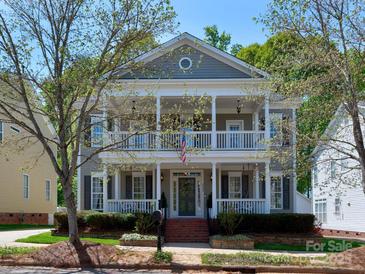 Charming two-story home with a double porch, landscaped yard, and a welcoming facade at 15323 Barnsbury Dr, Huntersville, NC 28078