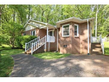 Charming brick home featuring a well-manicured lawn, complemented by lush trees and a welcoming entryway at 1730 Deer St, Charlotte, NC 28214