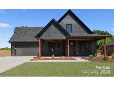 Stylish home with vertical siding, covered porch, green lawn, and attached two-car garage at 32531 Buchanan Ln, Albemarle, NC 28001