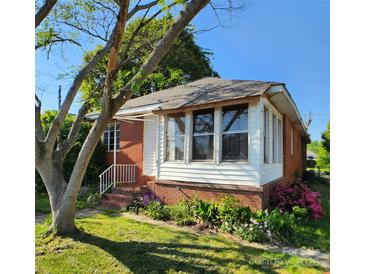Charming single-story home featuring brick accents, a sunroom, and a well-maintained lawn and garden at 40 Ranlo Ave, Gastonia, NC 28054