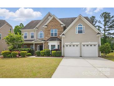Charming home with a two-car garage, well-manicured lawn, and lush landscaping at 8923 Happiness Rd, Harrisburg, NC 28075