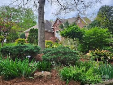 A beautiful brick home is set back from the street and adorned with lush landscaping and mature trees at 915 Houston Dr, Monroe, NC 28110