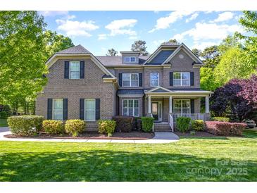 Stunning brick home with lush landscaping and a welcoming front porch at 10328 Lemington Dr, Mint Hill, NC 28227
