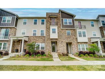 Beautiful three-story townhome featuring stone accents and manicured landscaping at 2533 Ensemble Ct, Charlotte, NC 28262