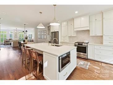 Bright white kitchen featuring a large center island with barstool seating, stainless appliances, and open to the living spaces at 2621 Huntman Way, Charlotte, NC 28226