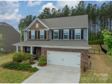 Charming brick and blue two-story home with a two-car garage and manicured front lawn at 127 Slip Shot Ln, Troutman, NC 28166