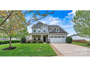 Charming two-story home boasts manicured lawn, stone accents, attached two-car garage, and inviting covered front porch at 1617 Post Ct, Gastonia, NC 28054