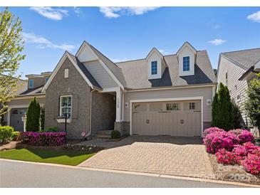 Charming home boasts stone accents, dormer windows, and a well-manicured front yard with colorful flowers at 17728 Jetton Green Loop, Cornelius, NC 28031