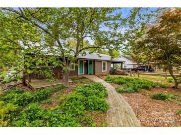 Charming cottage with a wooden walkway and a front porch with a wooded landscaped yard and teal front doors at 2106 4Th Ne St, Hickory, NC 28601
