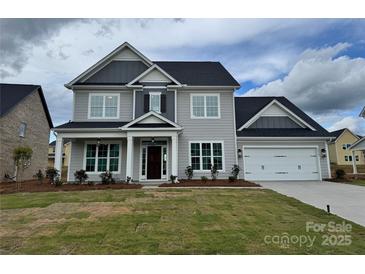 Charming two-story home with a gray exterior, a well-manicured lawn and an attached two car garage at 4038 Gardenia Dr # 0114, Harrisburg, NC 28075
