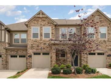 Charming townhome featuring stone accents, a tan garage door, and a well-maintained yard at 5684 Garrow Glen Rd # 96, Charlotte, NC 28278