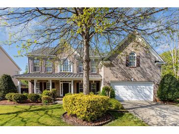 Charming brick two-story home featuring a covered porch and a well-manicured front yard with mature trees at 6941 Augustine Way, Charlotte, NC 28270