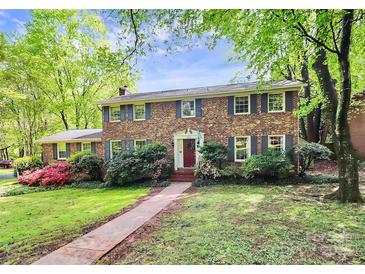 Charming brick home featuring lush landscaping, a manicured lawn, and a welcoming red front door at 7020 Leesburg Rd, Charlotte, NC 28215