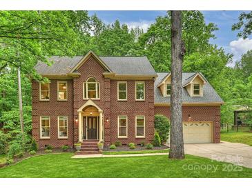 Charming two-story brick home with a well-manicured lawn and mature trees at 7067 Rocky Falls Rd, Charlotte, NC 28211