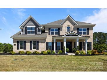 Stunning brick two-story home with a manicured lawn and charming front porch at 1052 Harlow'S Crossing Dr, Weddington, NC 28104