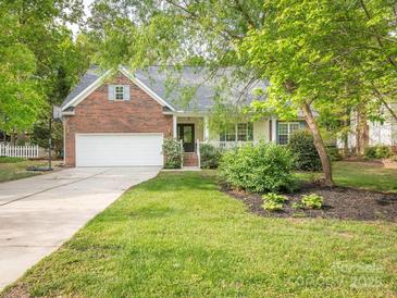 Charming brick and siding home featuring an attached garage, a well-maintained lawn, and mature trees at 3033 Beech Ct, Indian Trail, NC 28079