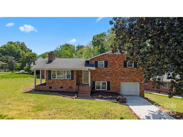 Charming brick home with a well-manicured lawn, attached garage, and inviting front porch under a sunny, blue sky at 5301 Baker Dr, Charlotte, NC 28210