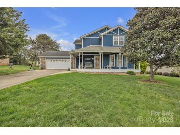 Charming two-story blue home featuring a spacious front yard and an attached garage with a basketball hoop at 63 Frost Ln, Taylorsville, NC 28681