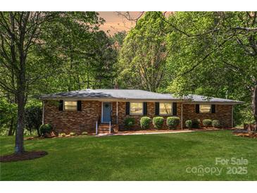 Charming brick home featuring a lush lawn, mature trees, and manicured landscaping creating lovely curb appeal at 6325 Elmwood Cir, Charlotte, NC 28214