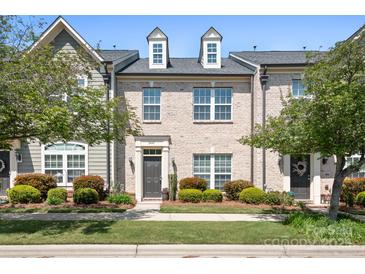 Charming townhome boasts beautiful brick facade, manicured landscaping, and inviting entrance at 11447 Potters Row, Cornelius, NC 28031
