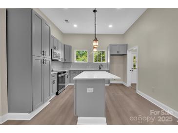 A spacious kitchen featuring gray cabinets, a central island, modern countertops, and stainless steel appliances at 126 Hemphill Ave, Chester, SC 29706