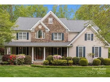 Charming two-story home featuring a stone facade, manicured landscaping and a welcoming front porch at 263 Fernbrook Dr, Mooresville, NC 28117
