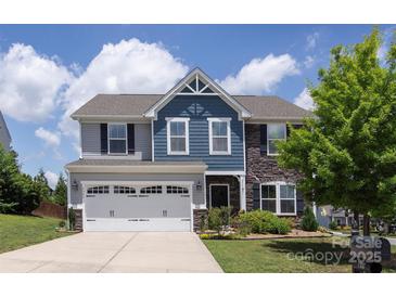 Charming two-story home with a manicured lawn, two car garage, and a mix of stone and blue toned siding at 7397 Mill Ruins Sw Ave, Concord, NC 28025
