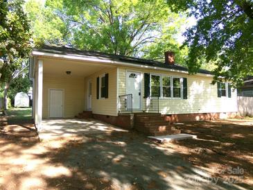 Charming single-story home with a covered carport, lush green trees, and a well-manicured lawn at 906 N 11Th St, Albemarle, NC 28001