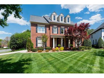 Beautiful brick home featuring a lush front lawn, mature trees, and classic architectural details at 12122 Camden Trail Ct, Charlotte, NC 28277