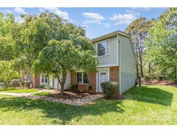 Charming townhome with a brick facade, lush lawn, and a mature tree providing shade at 7507 Holly Grove Ct, Charlotte, NC 28227