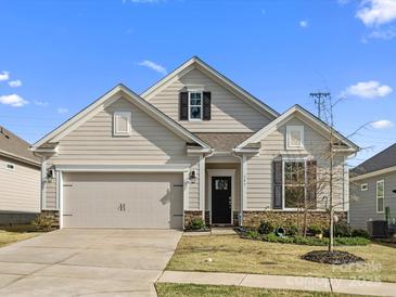 Charming single-story home with beige siding, stone accents, well-manicured lawn, and an attached two-car garage at 797 Latrobe Dr, Iron Station, NC 28080