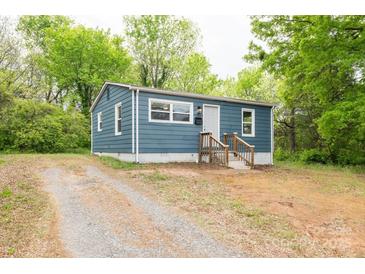 Charming blue single-story home featuring a gravel driveway surrounded by lush green trees at 1011 Rickert St, Statesville, NC 28677