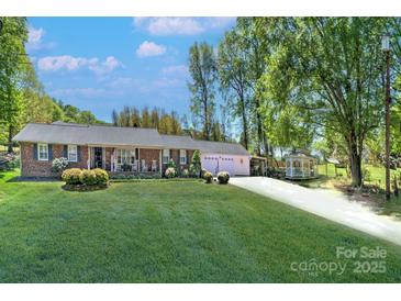 Charming brick ranch with a manicured lawn and a long driveway leading to a two-car garage at 212 Brookwood Dr, Salisbury, NC 28146