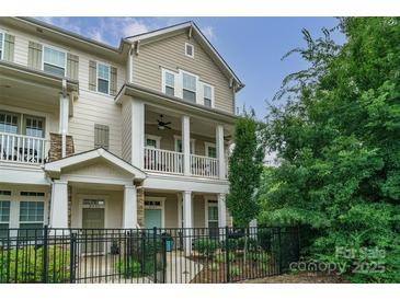Charming townhome with two stories, front porch, balcony, fenced yard, and neutral-colored siding at 2355 Crockett Park Pl, Charlotte, NC 28203