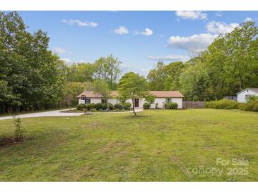Sprawling front yard with mature trees and a well-maintained lawn leads up to a charming ranch-style home at 7200 Monroe Rd, Charlotte, NC 28212