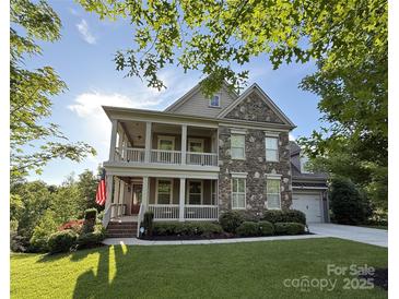 Charming two-story home featuring a stone facade, double porches, lush lawn, and attached garage at 14010 Promenade Dr, Huntersville, NC 28078